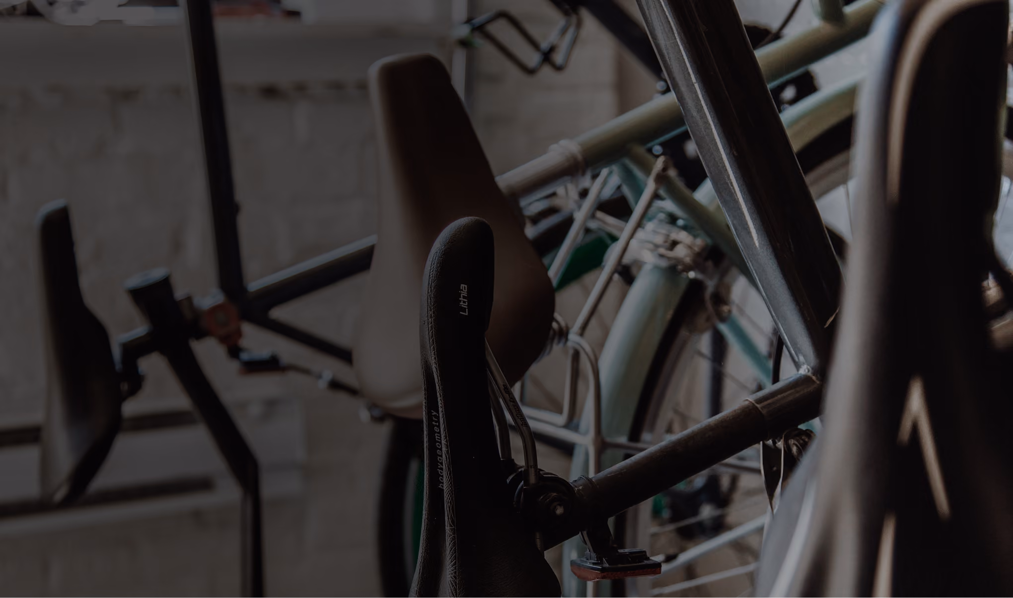 Close-up of bicycle seats and parts in a dimly lit indoor space.