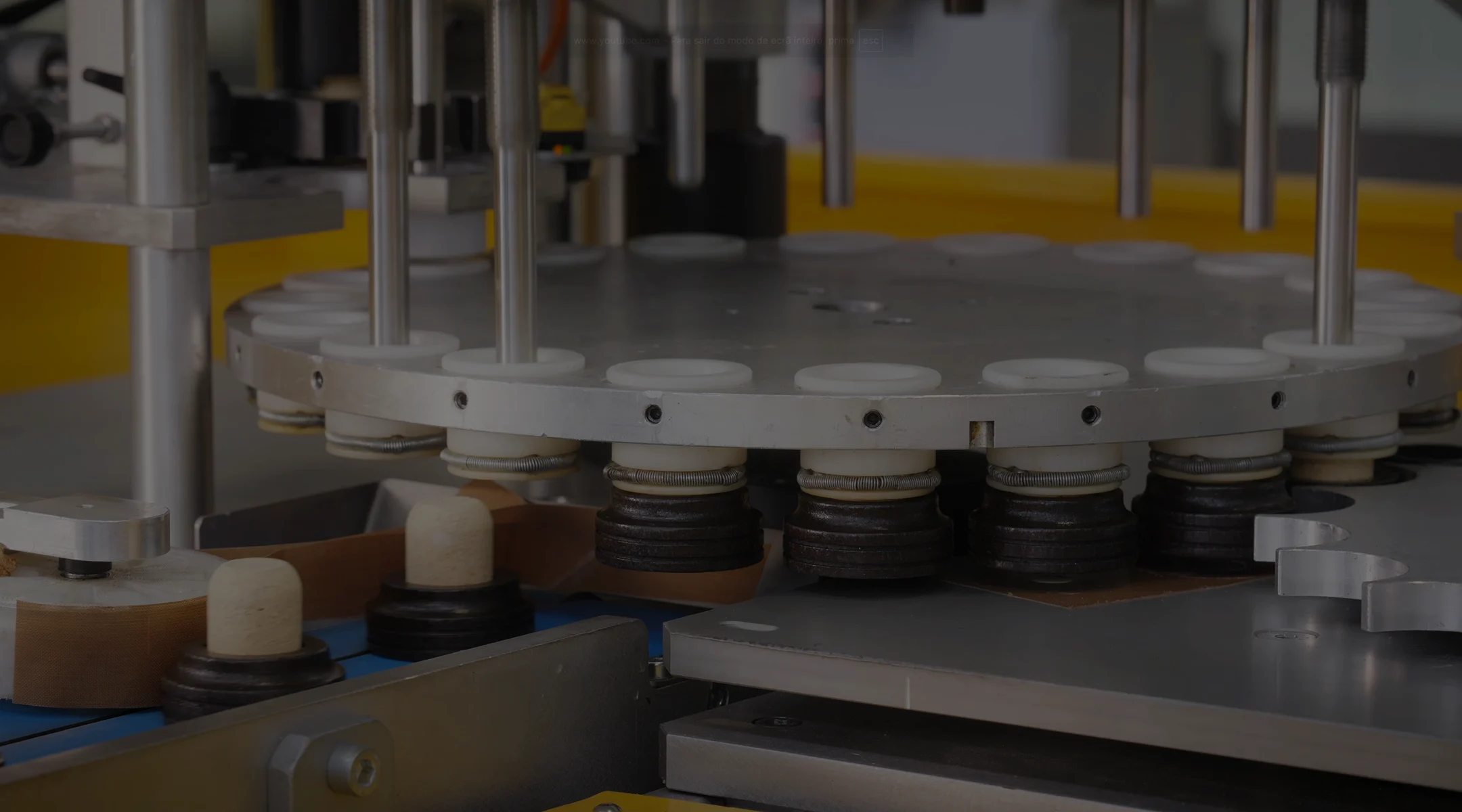 Rows of glass bottles on a metal table with a person’s hand placing some bottles in the background.