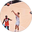 Joueur en blanc tirant un panier en suspension pendant un match de basket contre un joueur en rouge.