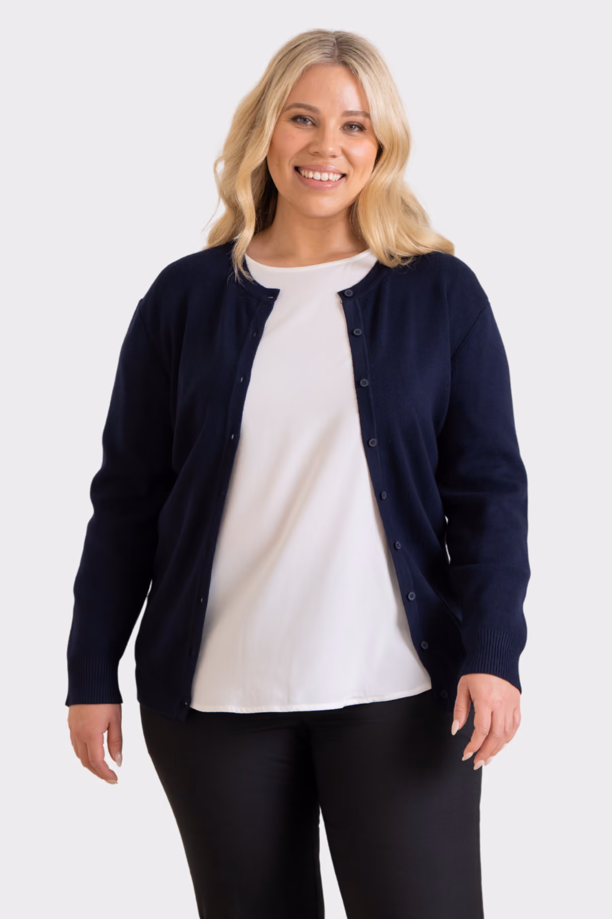 Woman wearing a navy corporate cardigan over a white top with black trousers