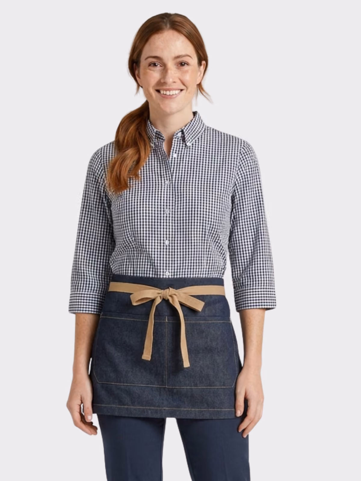 Woman wearing a navy check hospitality shirt with a denim waist apron