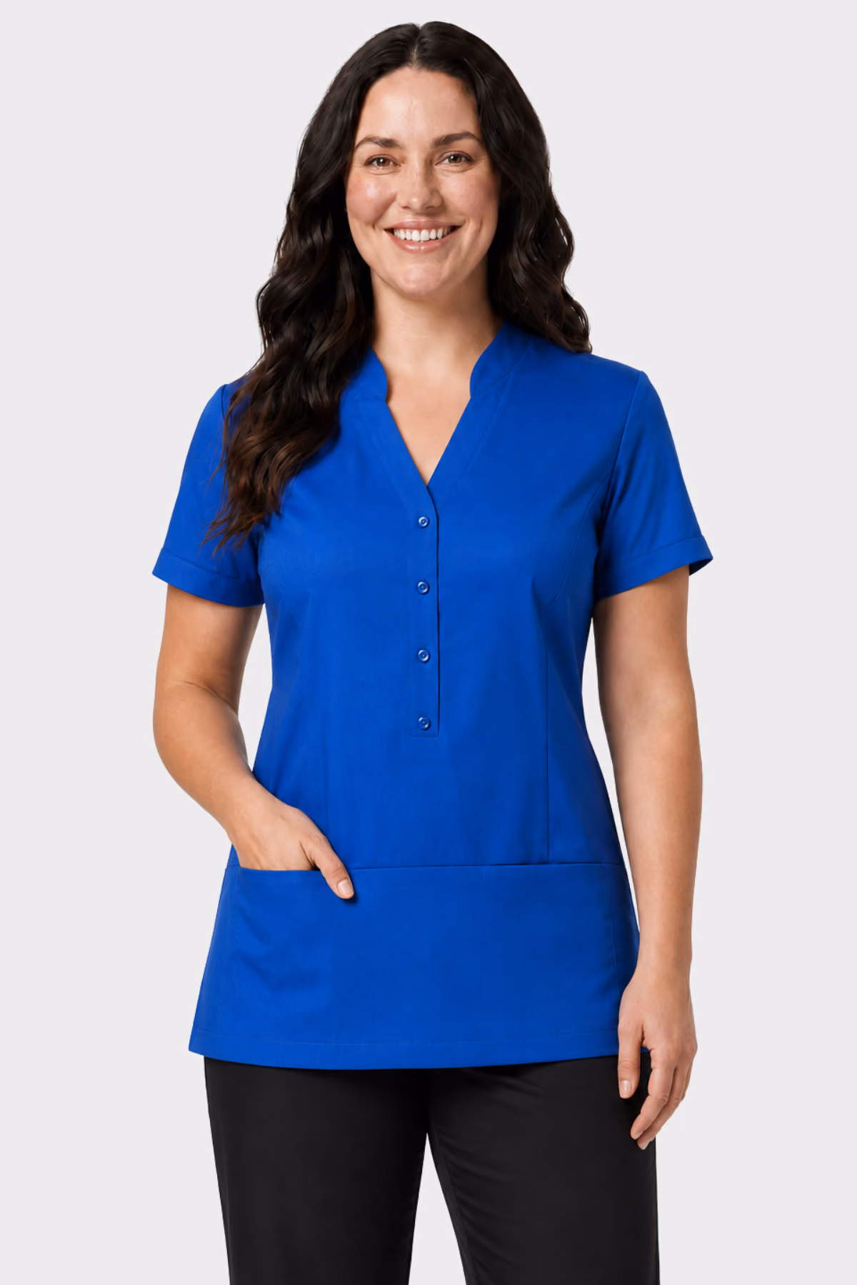 Woman wearing a bright blue healthcare tunic with front pockets and black trousers