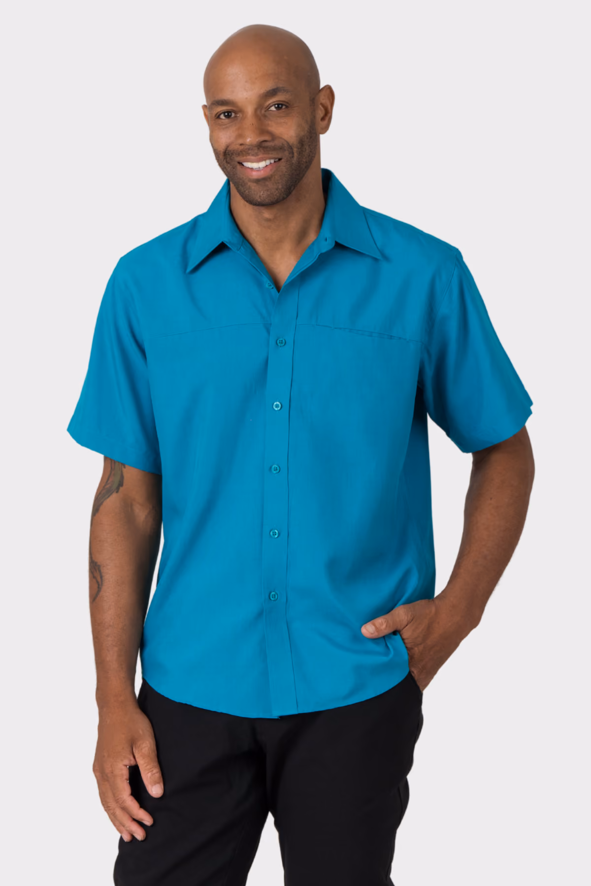 Man wearing a teal short-sleeve aged care shirt with black trousers