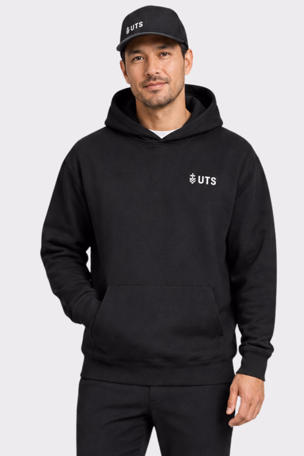 Man wearing a black university hoodie and matching cap with a printed logo