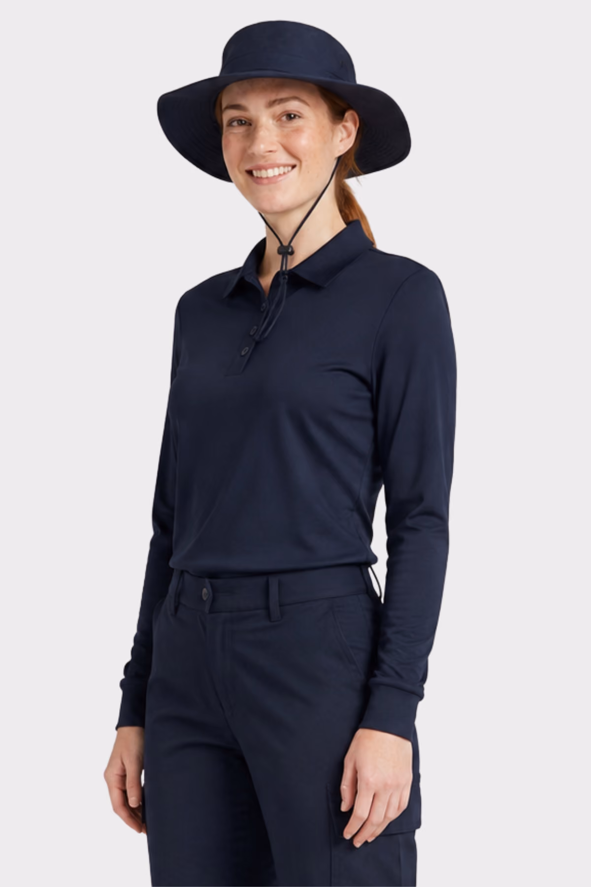 Woman wearing a navy long-sleeve polo, navy trousers and a navy wide-brim hat