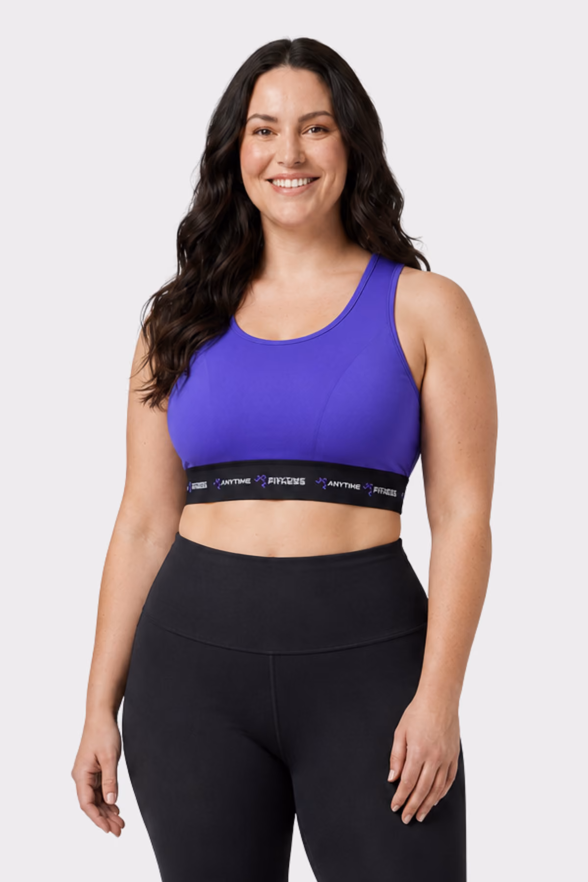 Woman wearing a purple sports crop top with black leggings