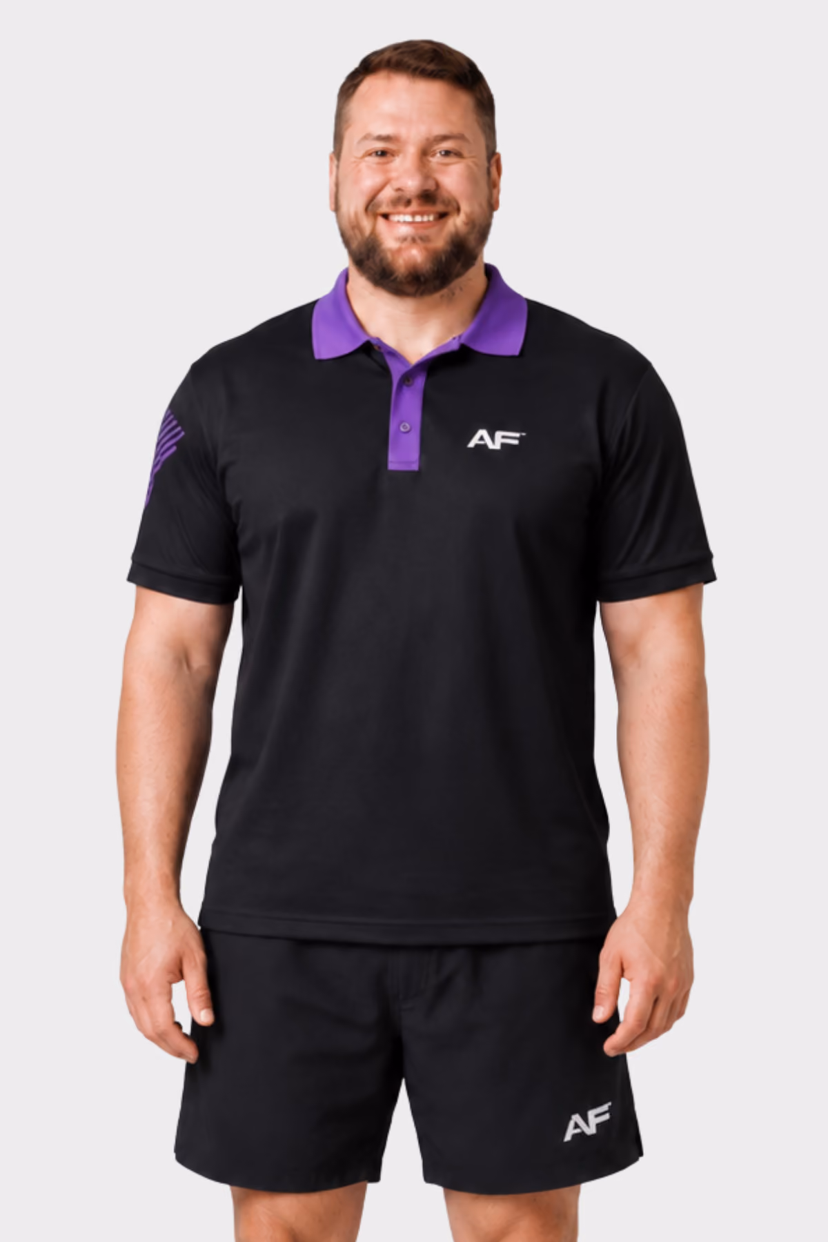 Man wearing a black and purple branded fitness polo with black shorts