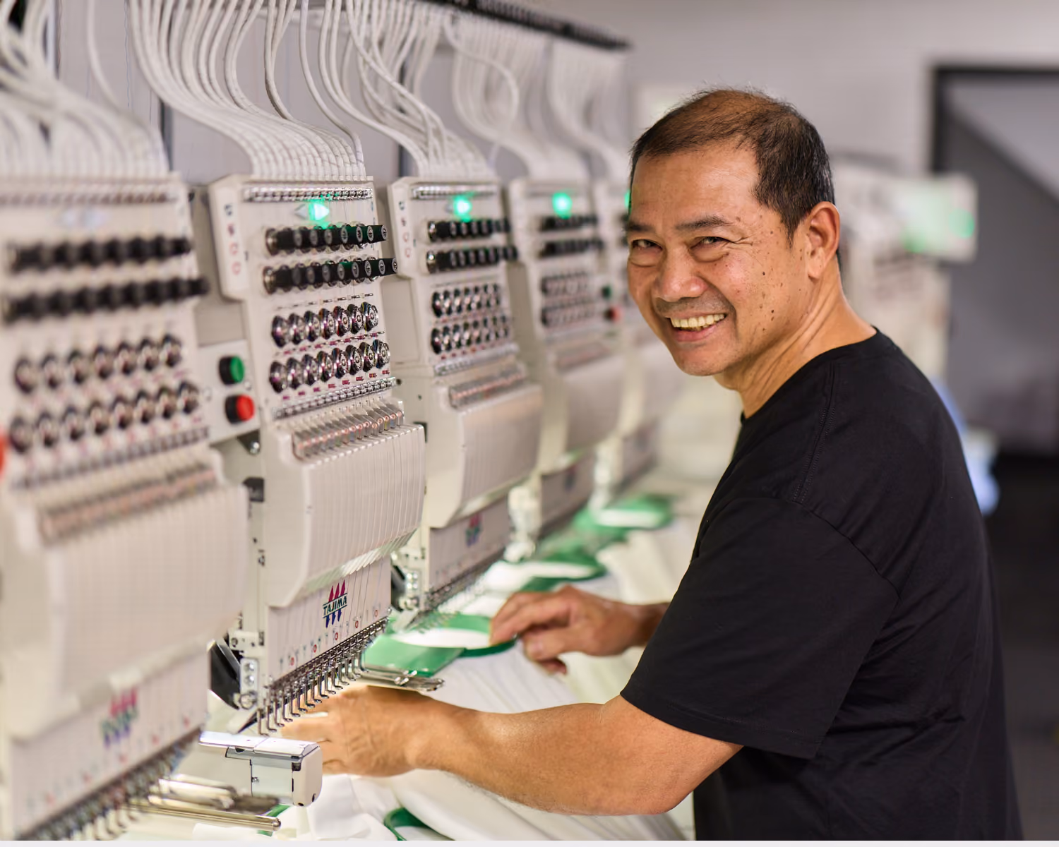 Embroidery machine stitching a logo onto a garment, operated by a technician