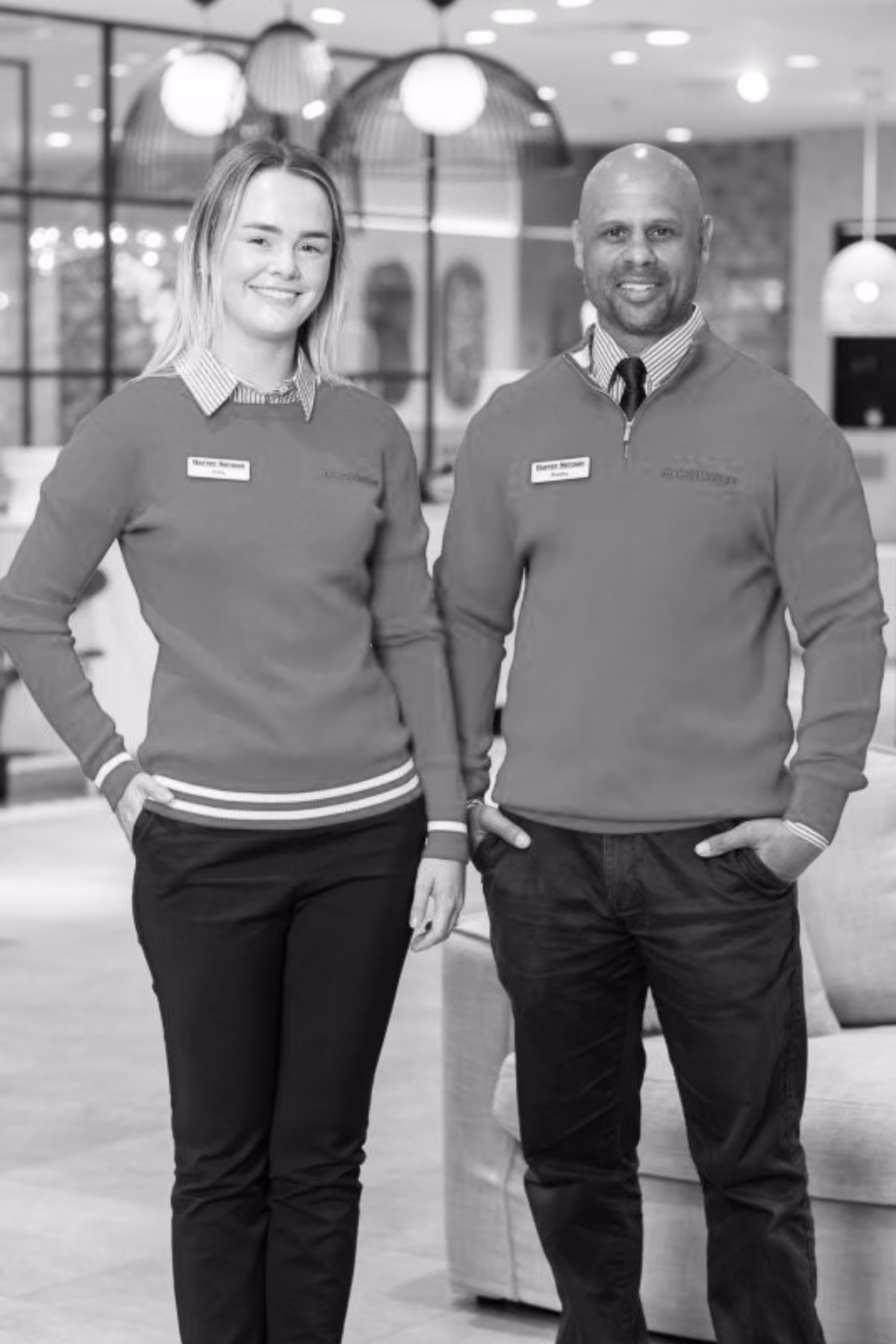 Two retail staff in matching branded knit jumpers standing in a store