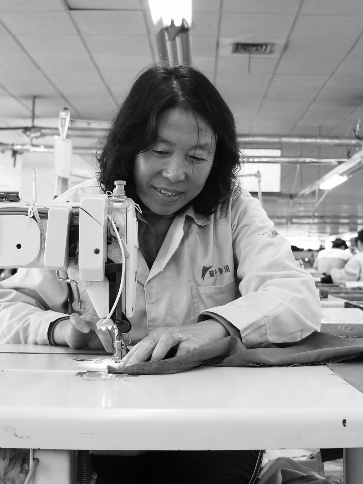 Garment worker sewing fabric at an industrial sewing machine in a factory