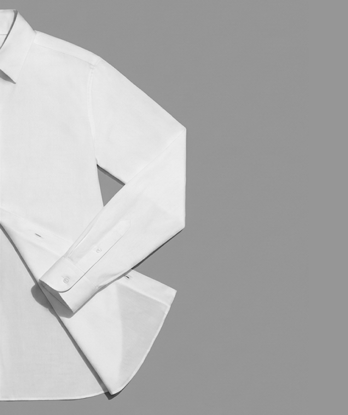 White cotton shirt laid flat on a grey background
