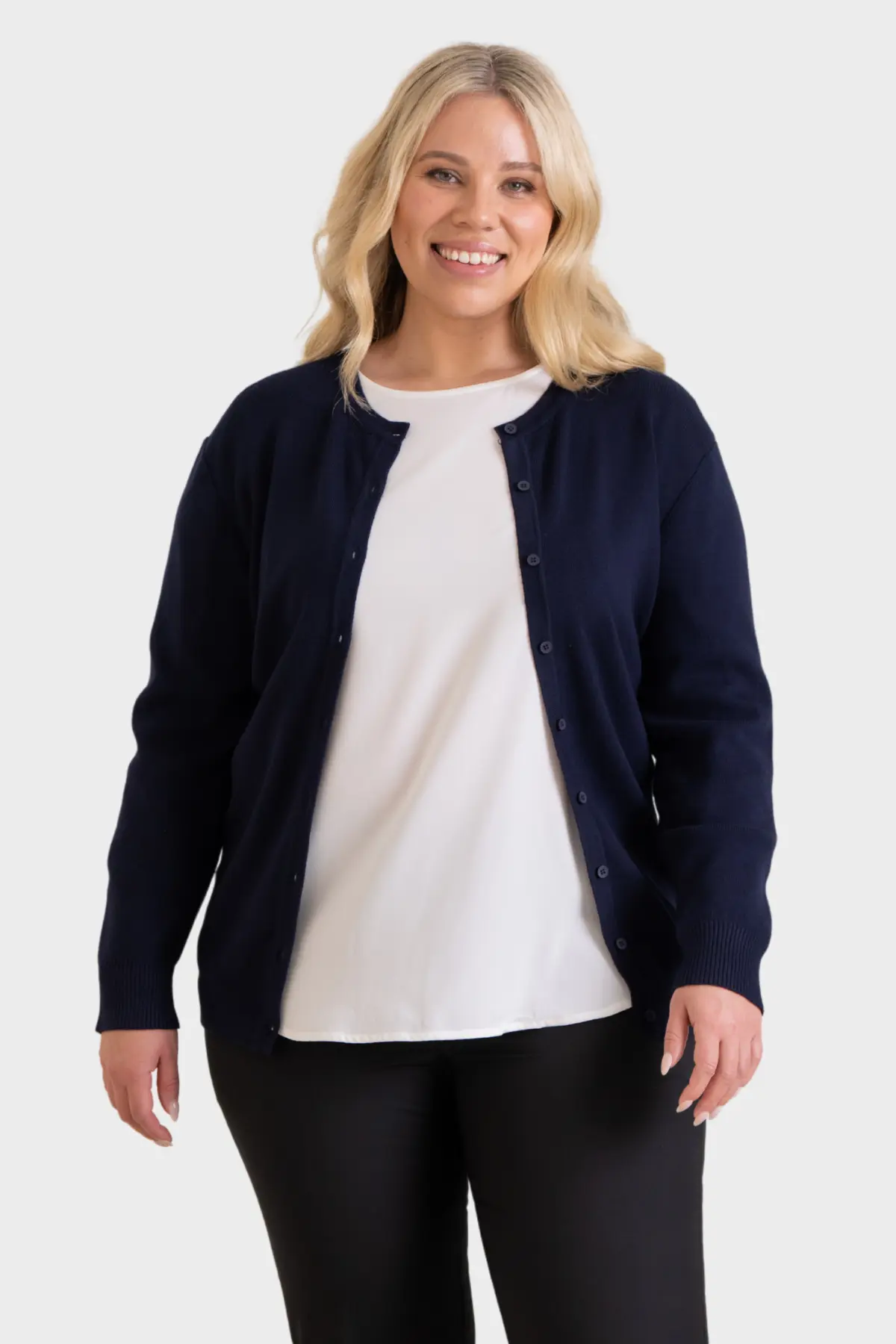 Woman wearing a navy button-up cardigan over a white top with black trousers