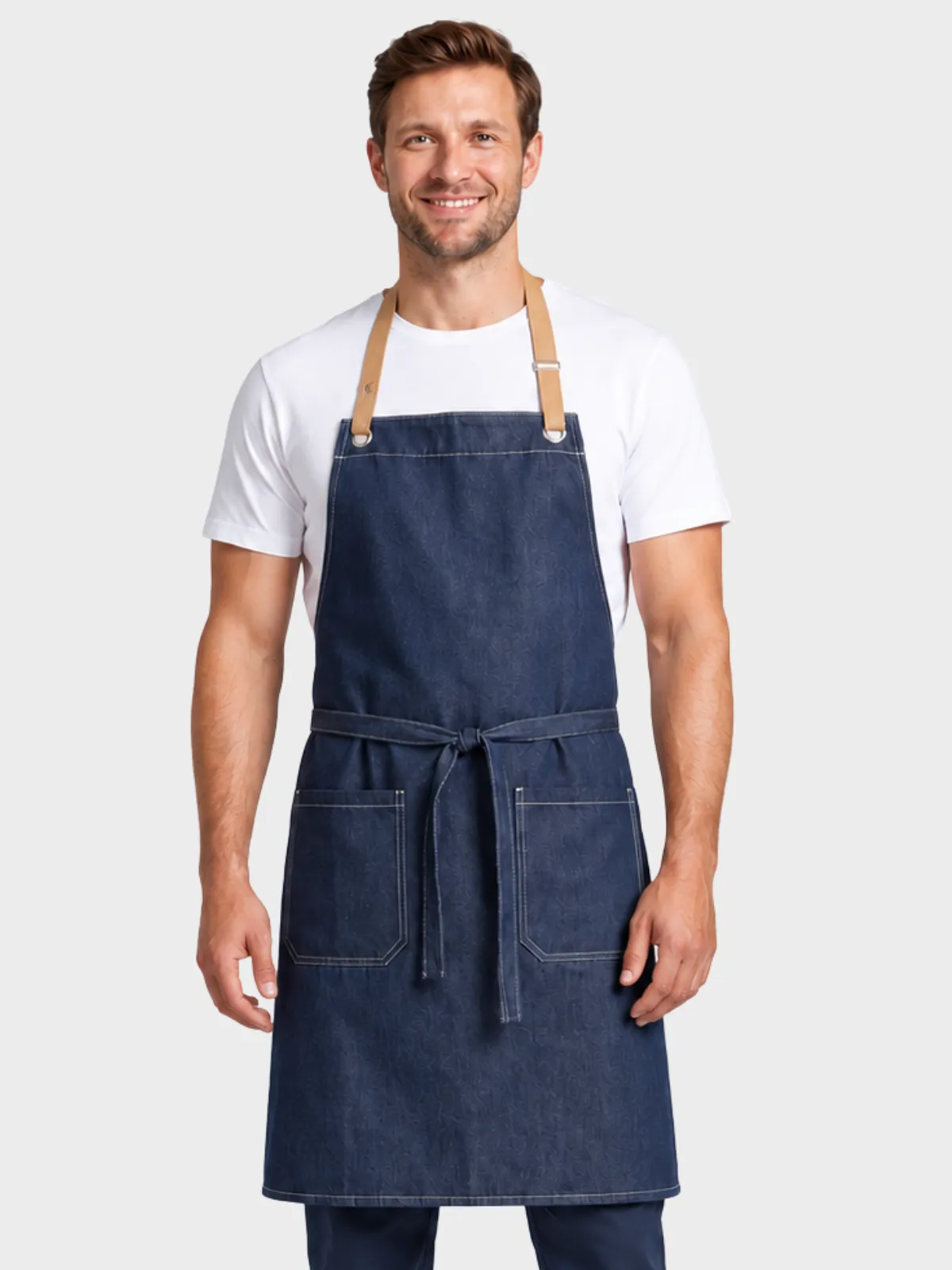 Man wearing a denim bib apron with tan leather straps over a white T-shirt