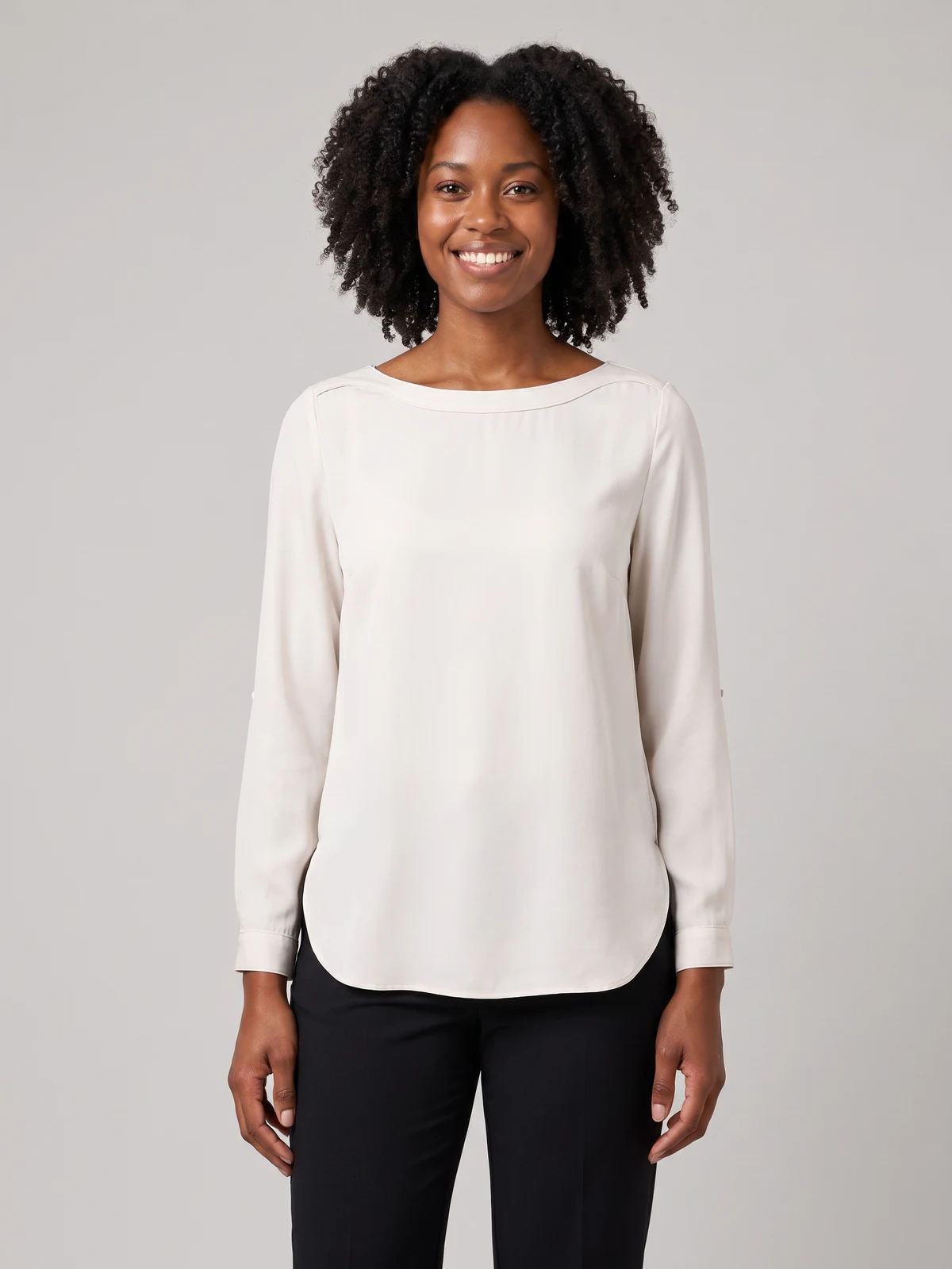 Woman wearing an ivory long-sleeve boat-neck blouse with black trousers