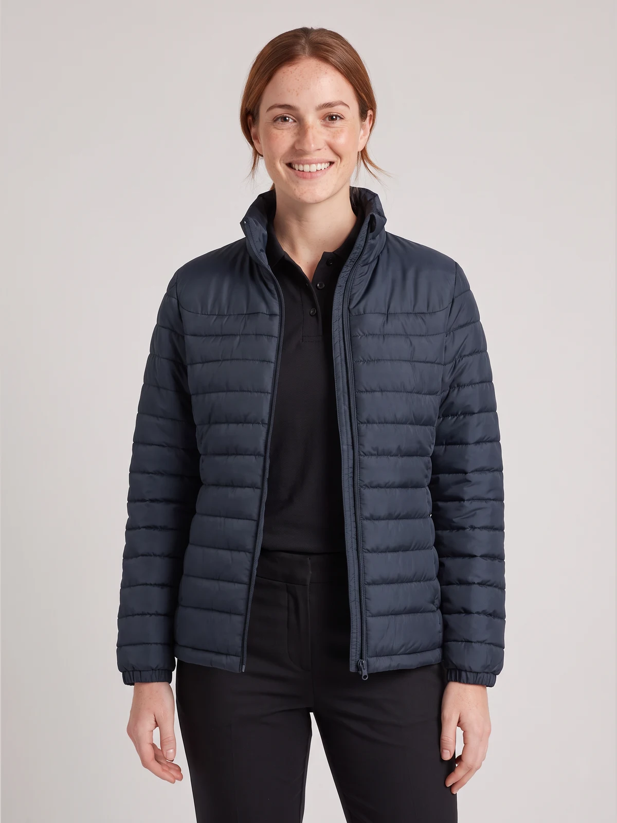 Woman wearing a navy quilted puffer jacket over a black polo
