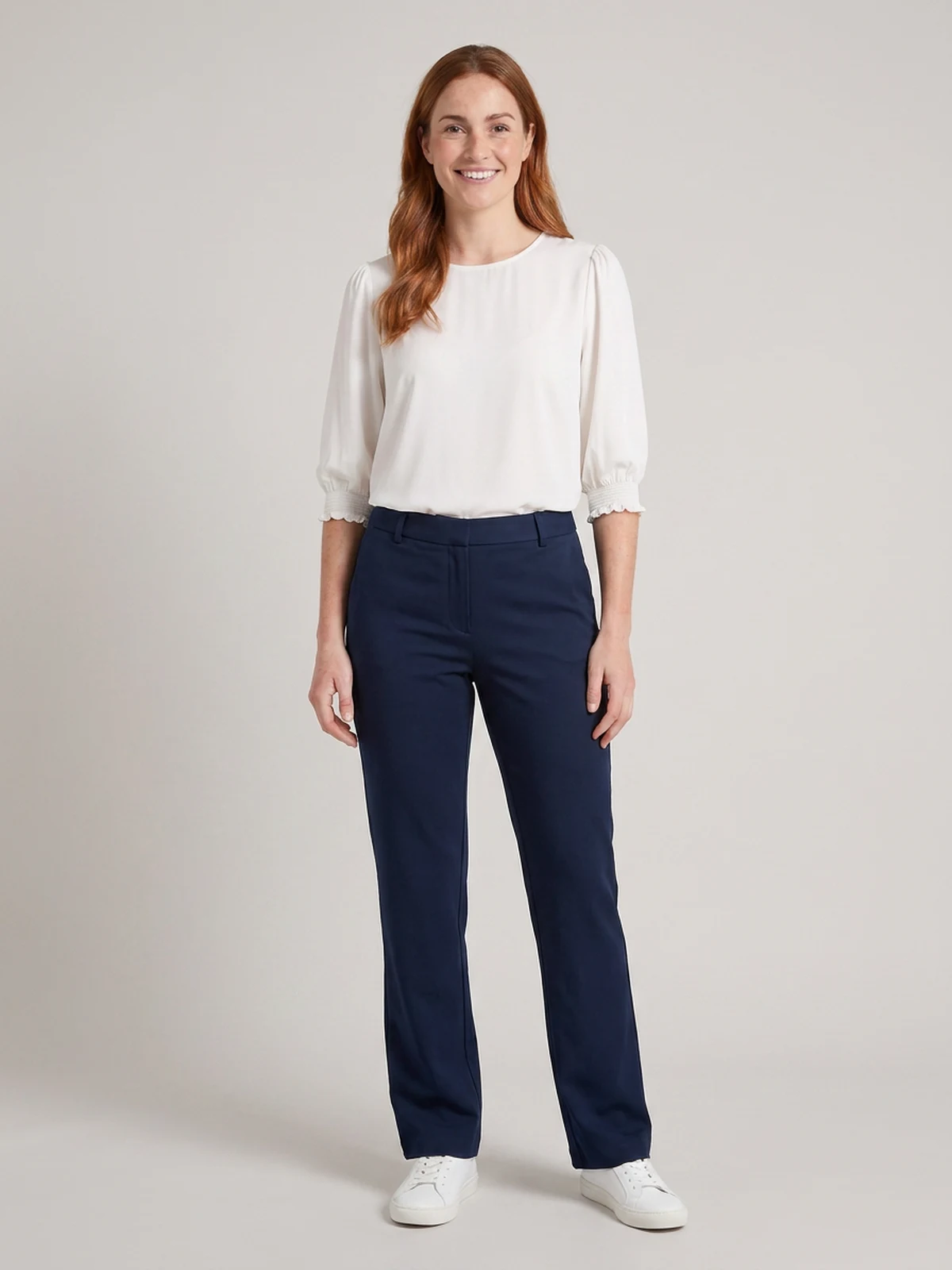 Woman wearing navy tailored trousers with a white puff-sleeve top