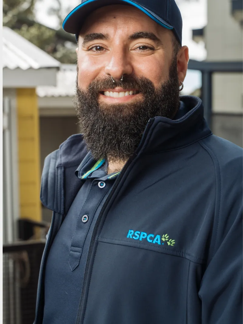 Smiling man in a navy RSPCA-branded zip jacket and cap