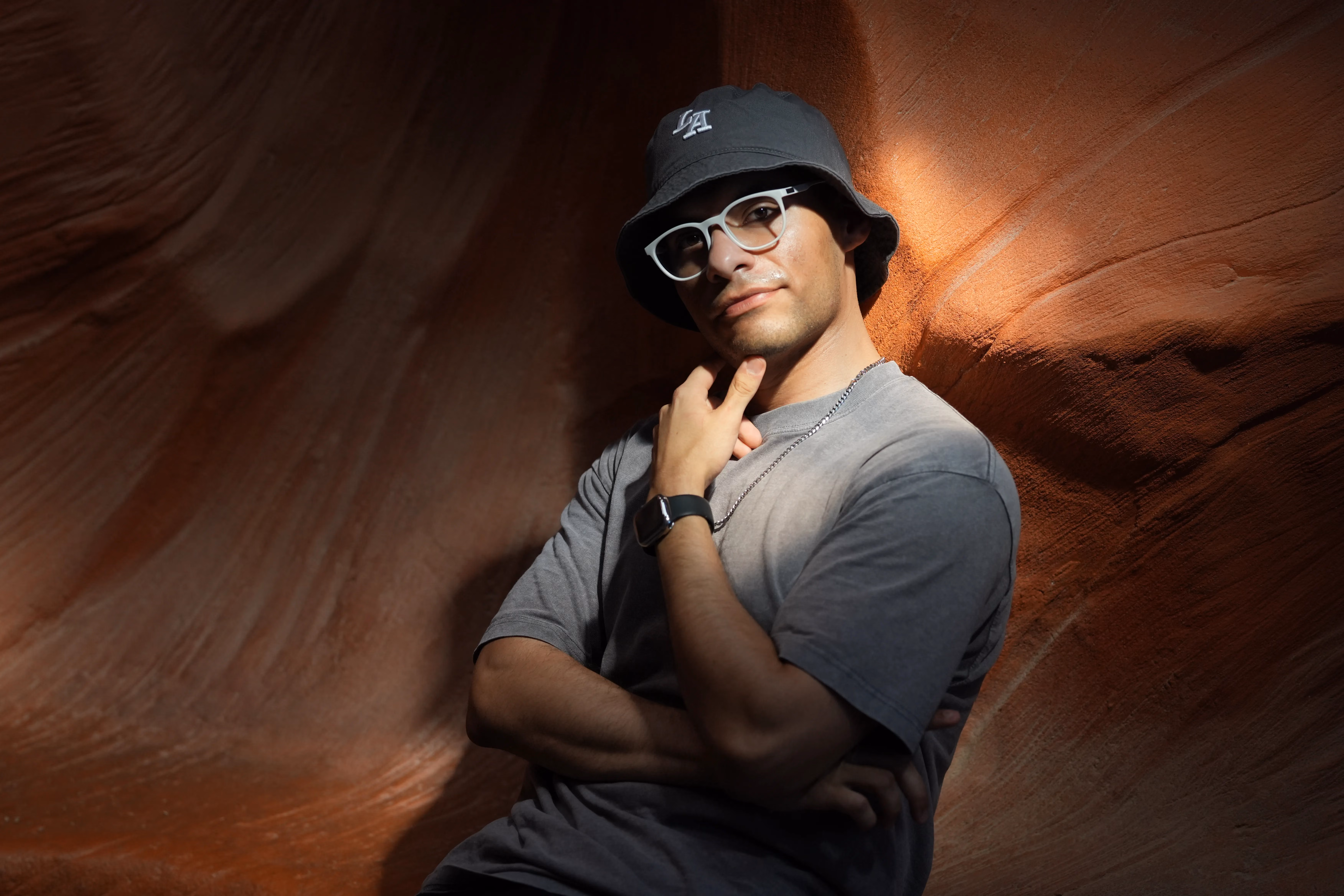 Moody portrait of a man in a bucket hat and glasses against glowing sandstone canyon walls, by Studio Bishop
