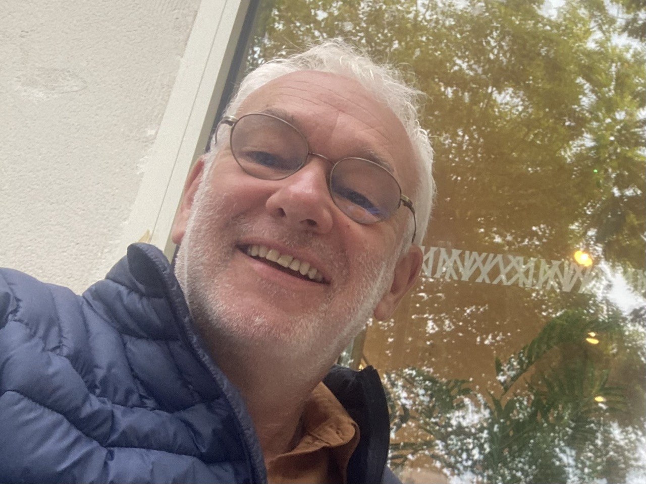 Glyn, smiling, in a navy jacket beneath autumn trees