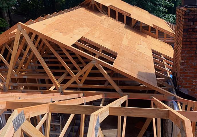 Wooden frame and plywood roof sheathing in progress on a residential house under construction.