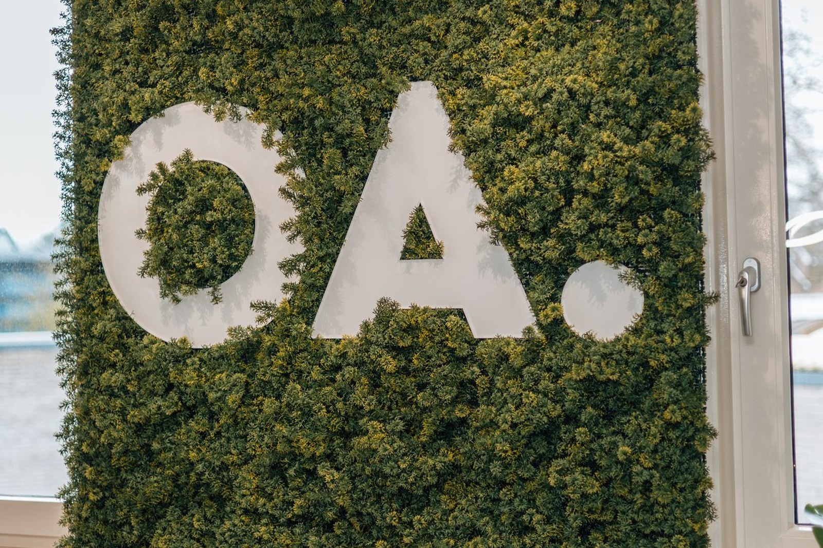 Groene mosswand met wit OA-logo in kantoorinterieur