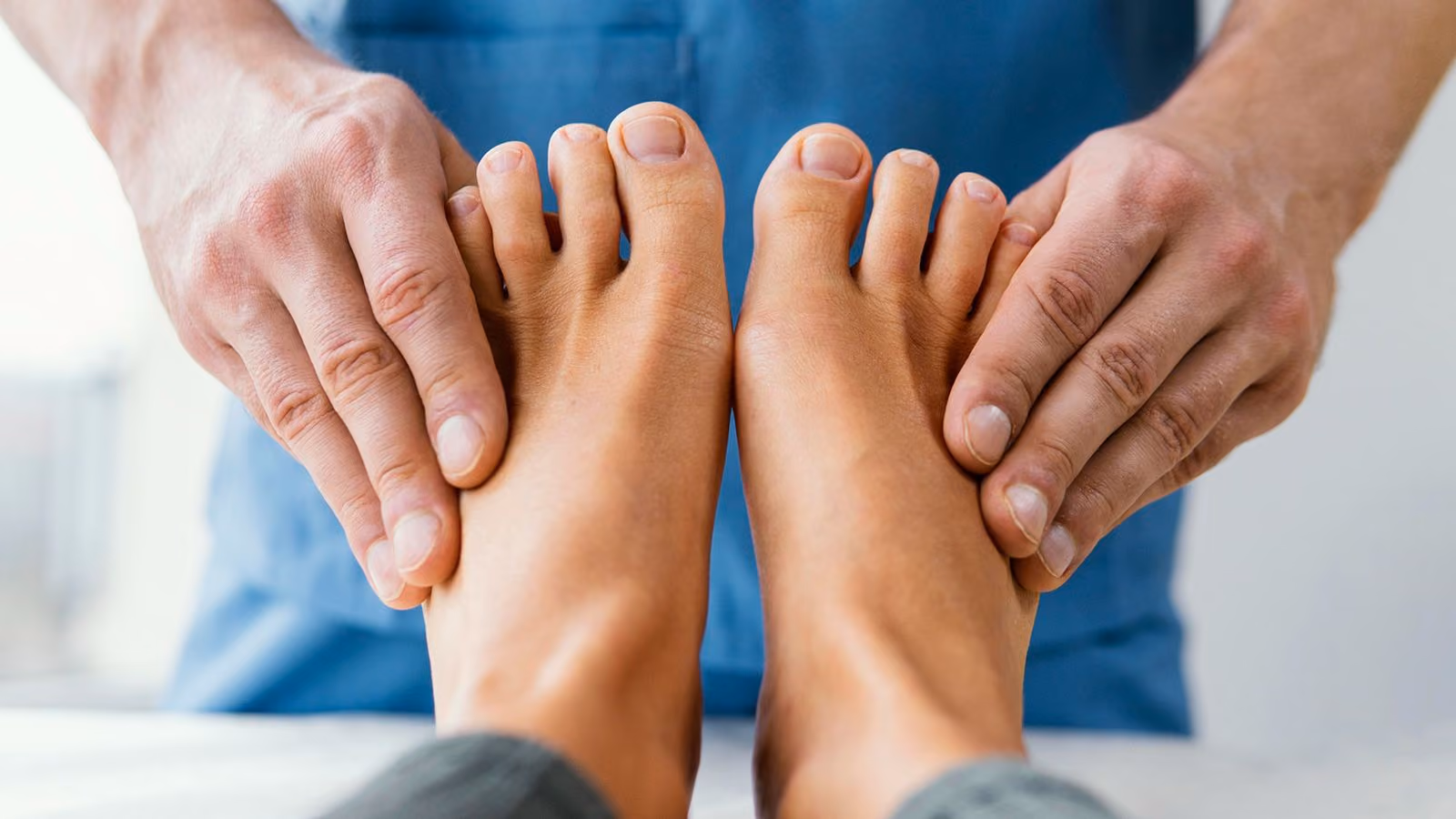 A podiatrist examining a pair of bare feet