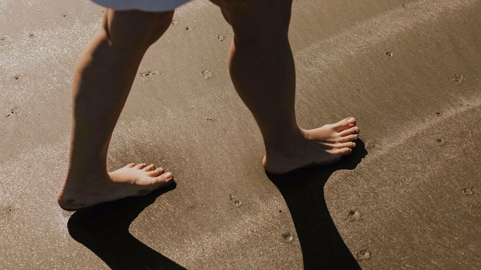 Bare legs and feet walking in the sand