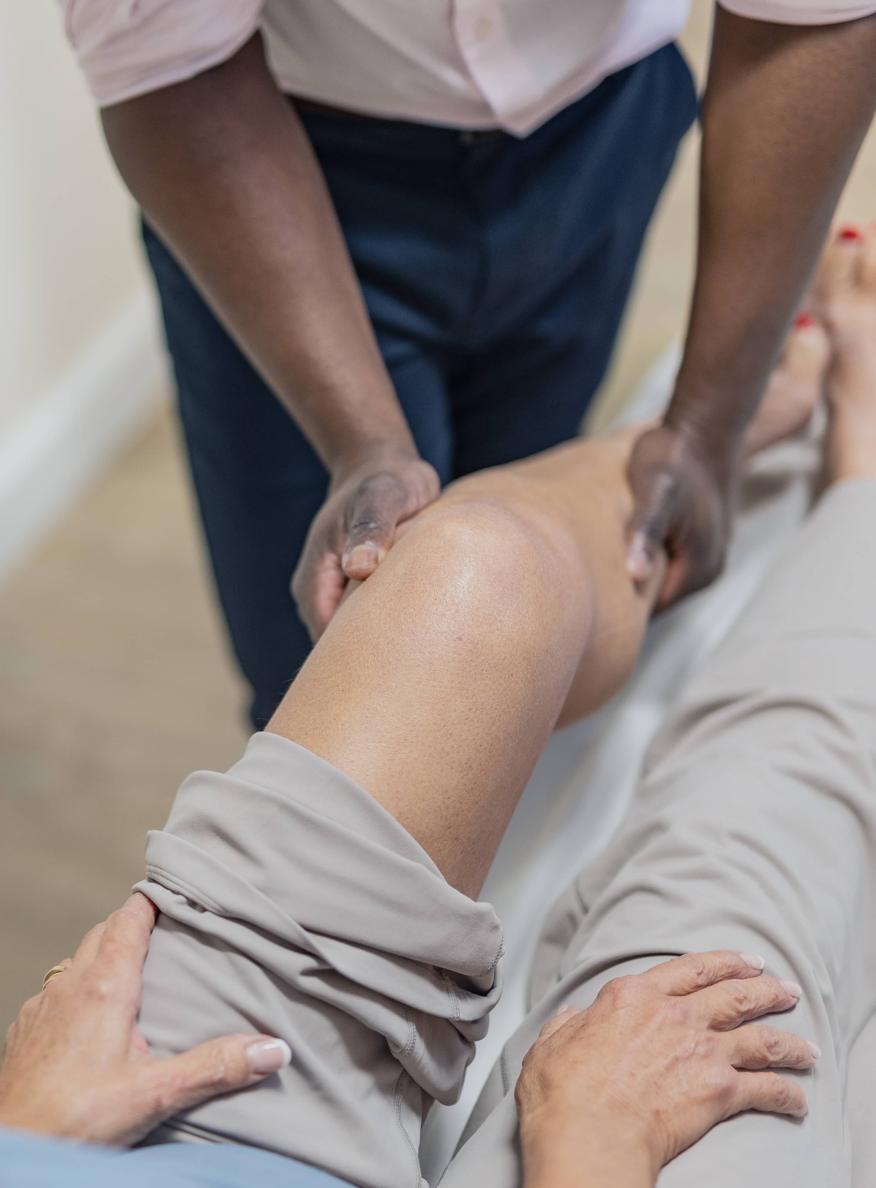 Mr oni holding the knee and calf of a female patient during an examination of meniscal tears.