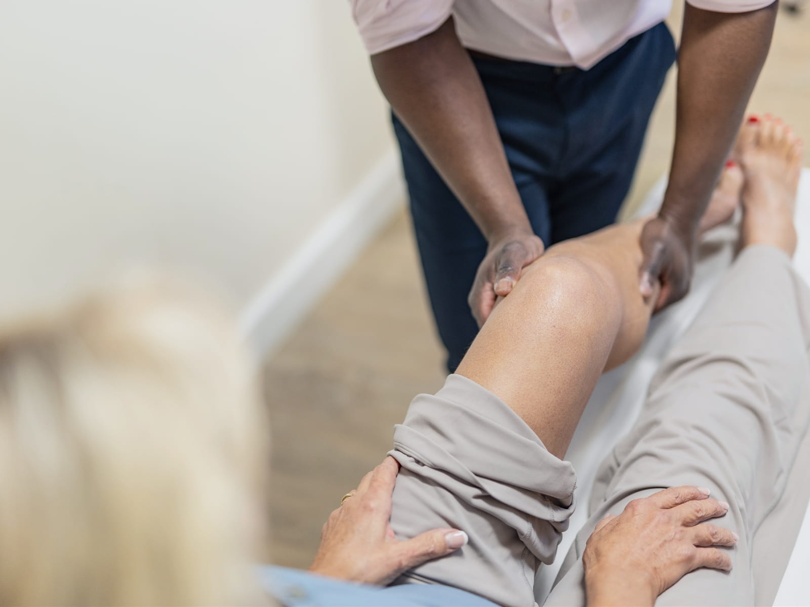 mr oni holding the female patient's leg during an exam, she is looking down at him doing this.