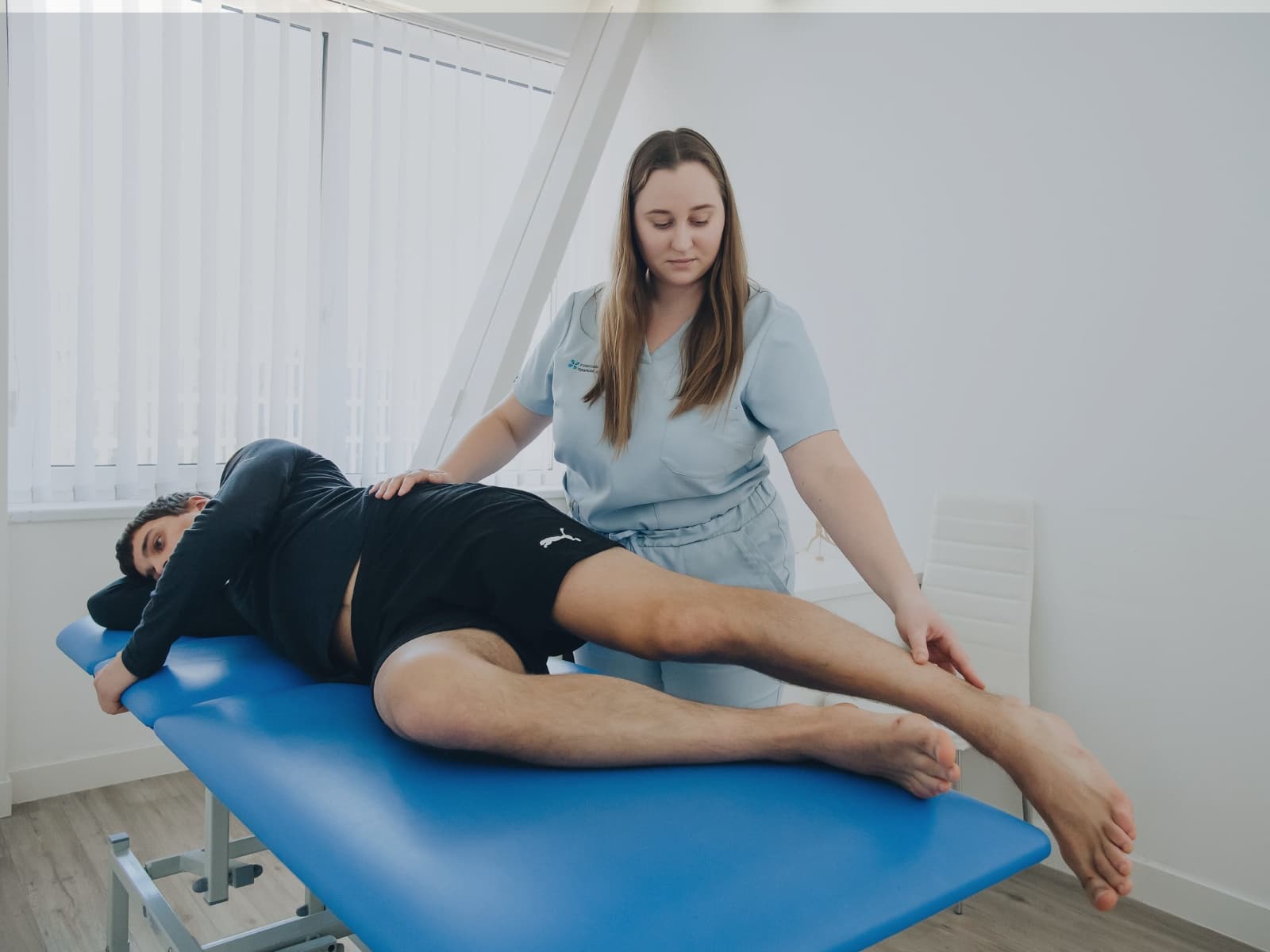a female physio working on a young male patient laying down on a physio couch.