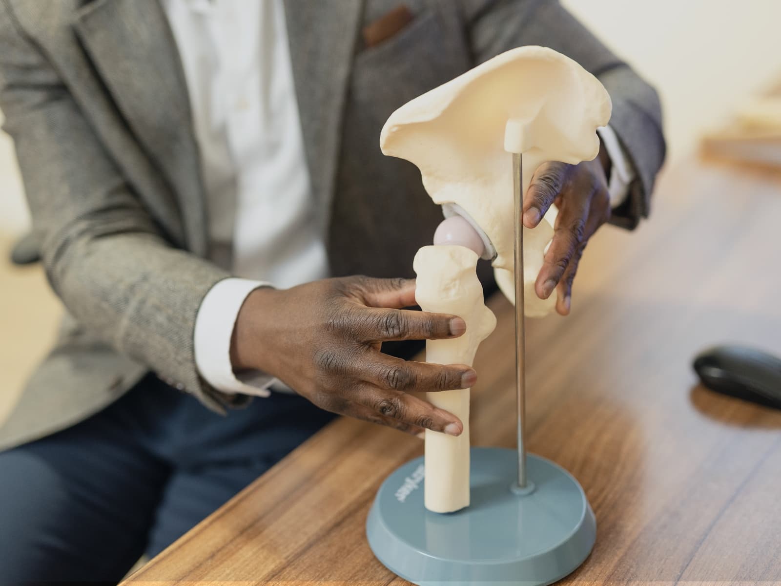 Mr Oni manipulating a medical model of a hip joint on his desk in front of a computer screen.