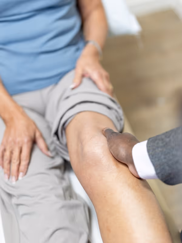 Mr oni examining a female patients knee whilst she is on the examination couch