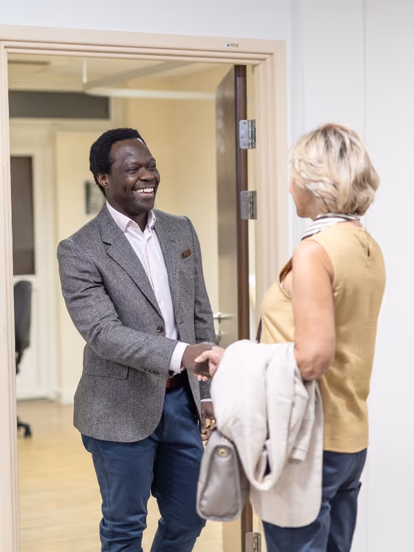 Mr oni shaking hands at the consulting room door whilst smiling
