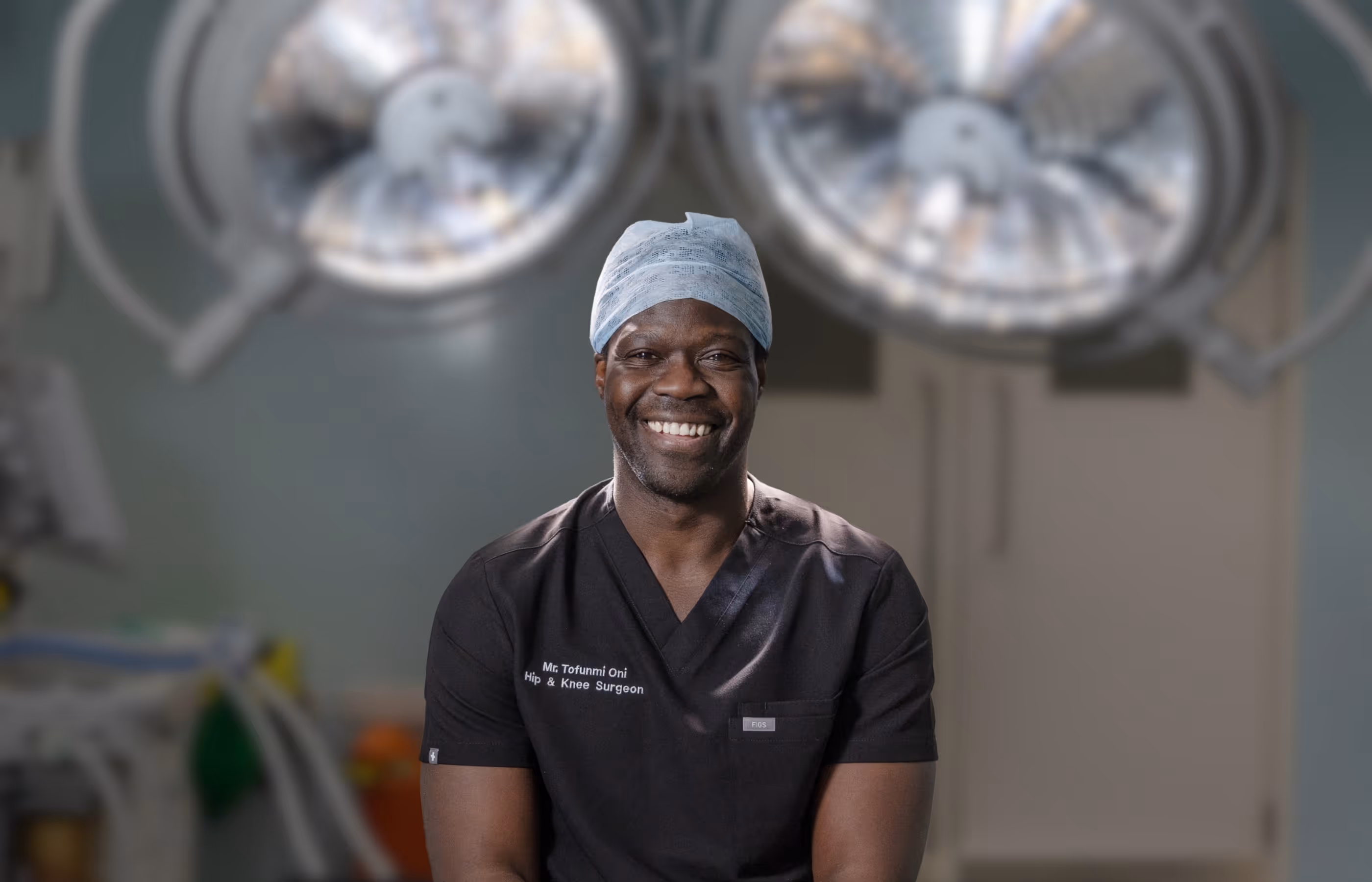 Mr Oni smiling widely at the camera with theatre lights blurred in the background appearing above him in the image