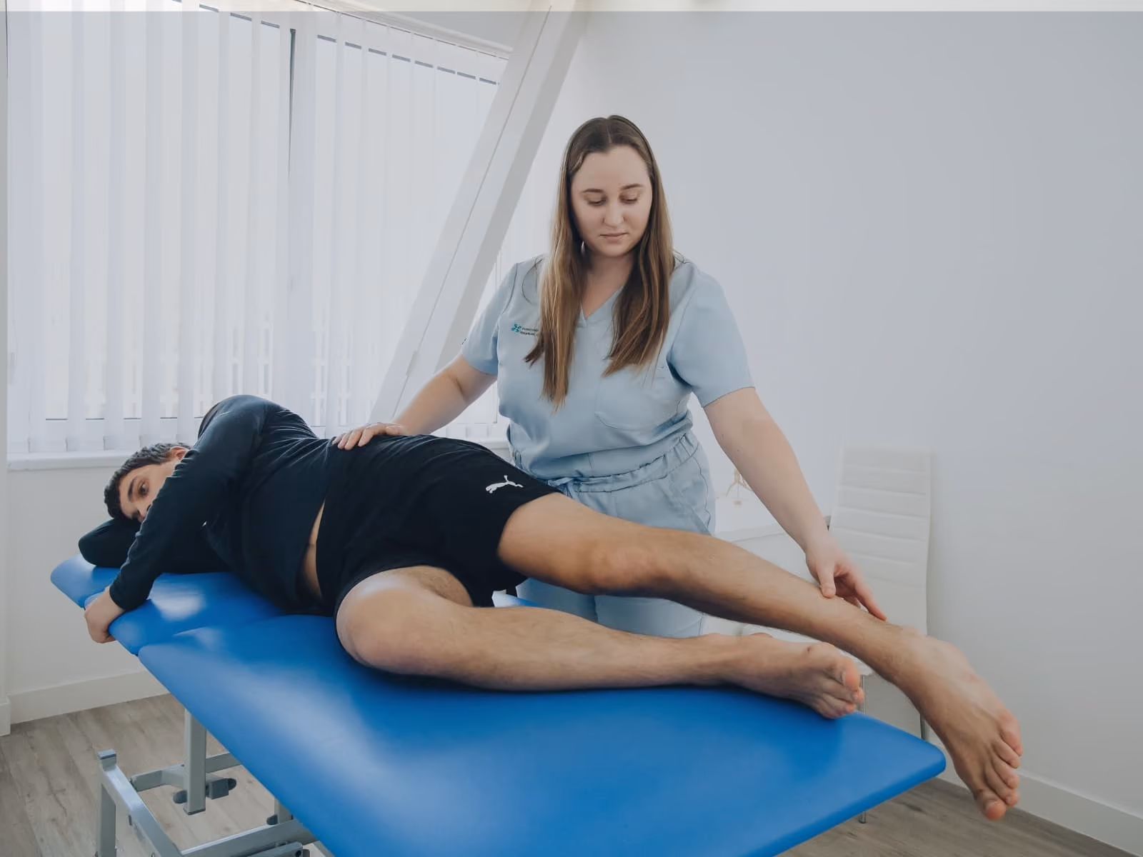 female physio working on a young man laying on a medical couch.