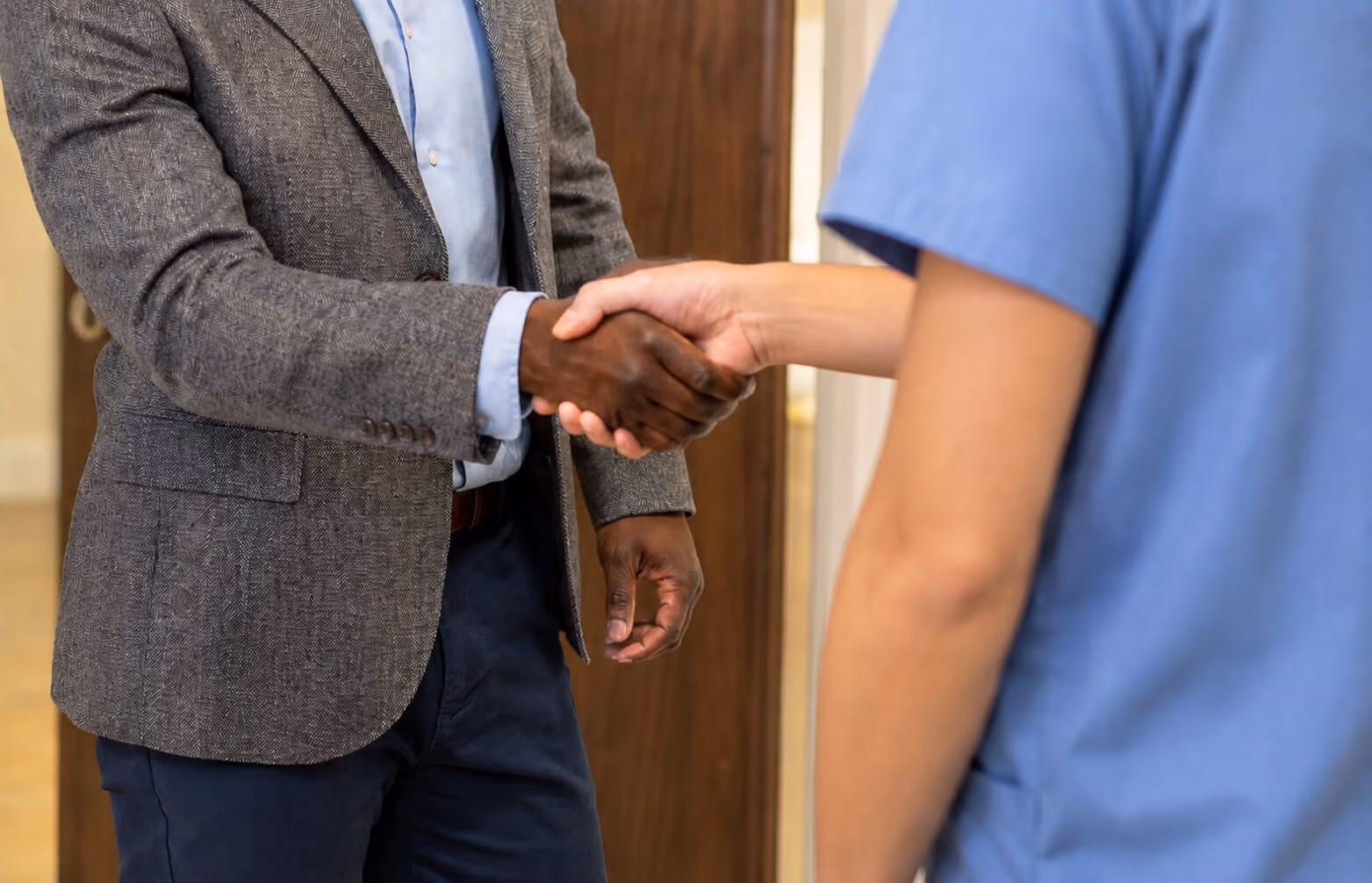 A close up image of Mr Oni shaking hands with another person wearing blue scrubs
