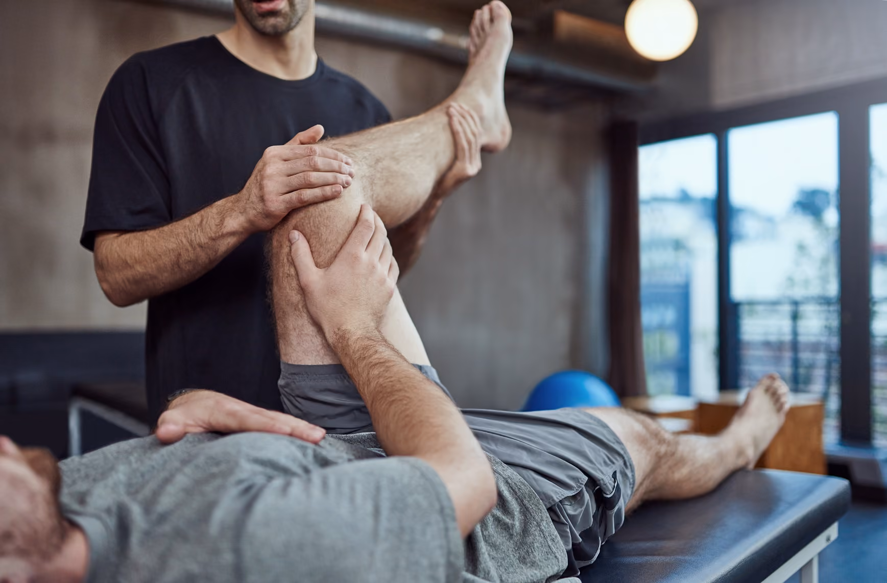 a physio manipulating someones leg and they are holding their knee