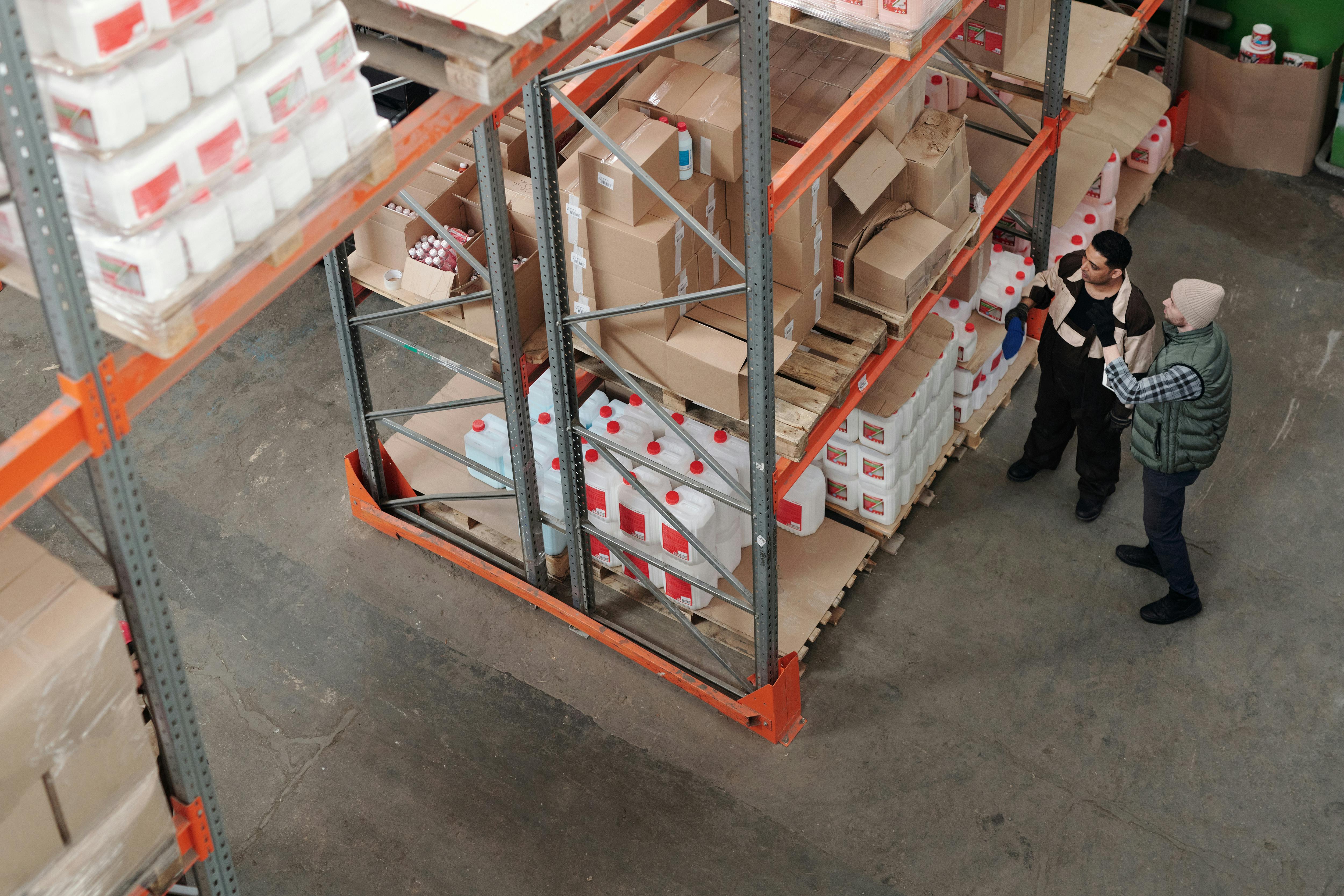 An overhead shot of an organized warehouse storage area with clearly labeled shelving zones, crates, and products.