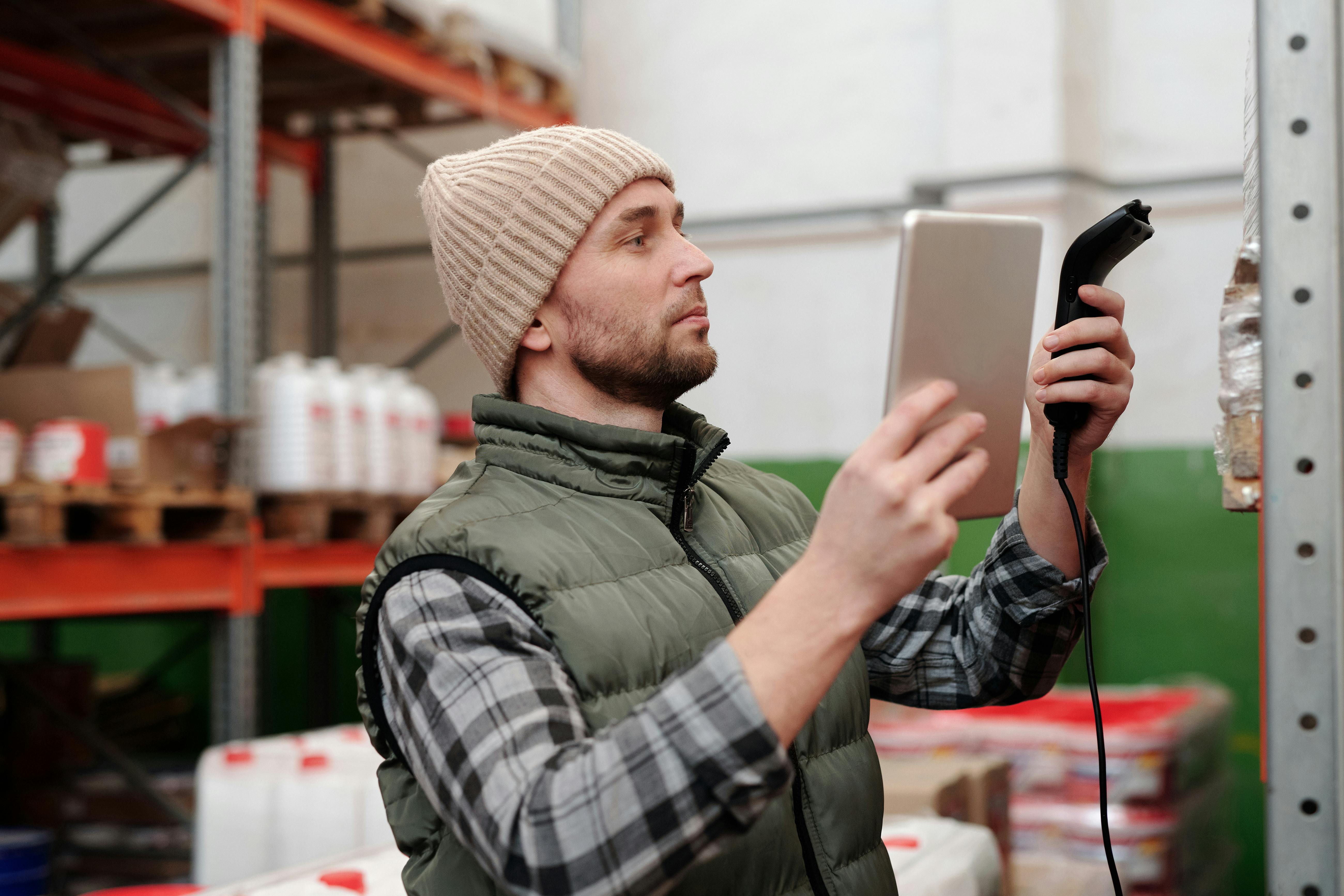 A warehouse worker holding a hanheld scanner to move inventory to a different bin
