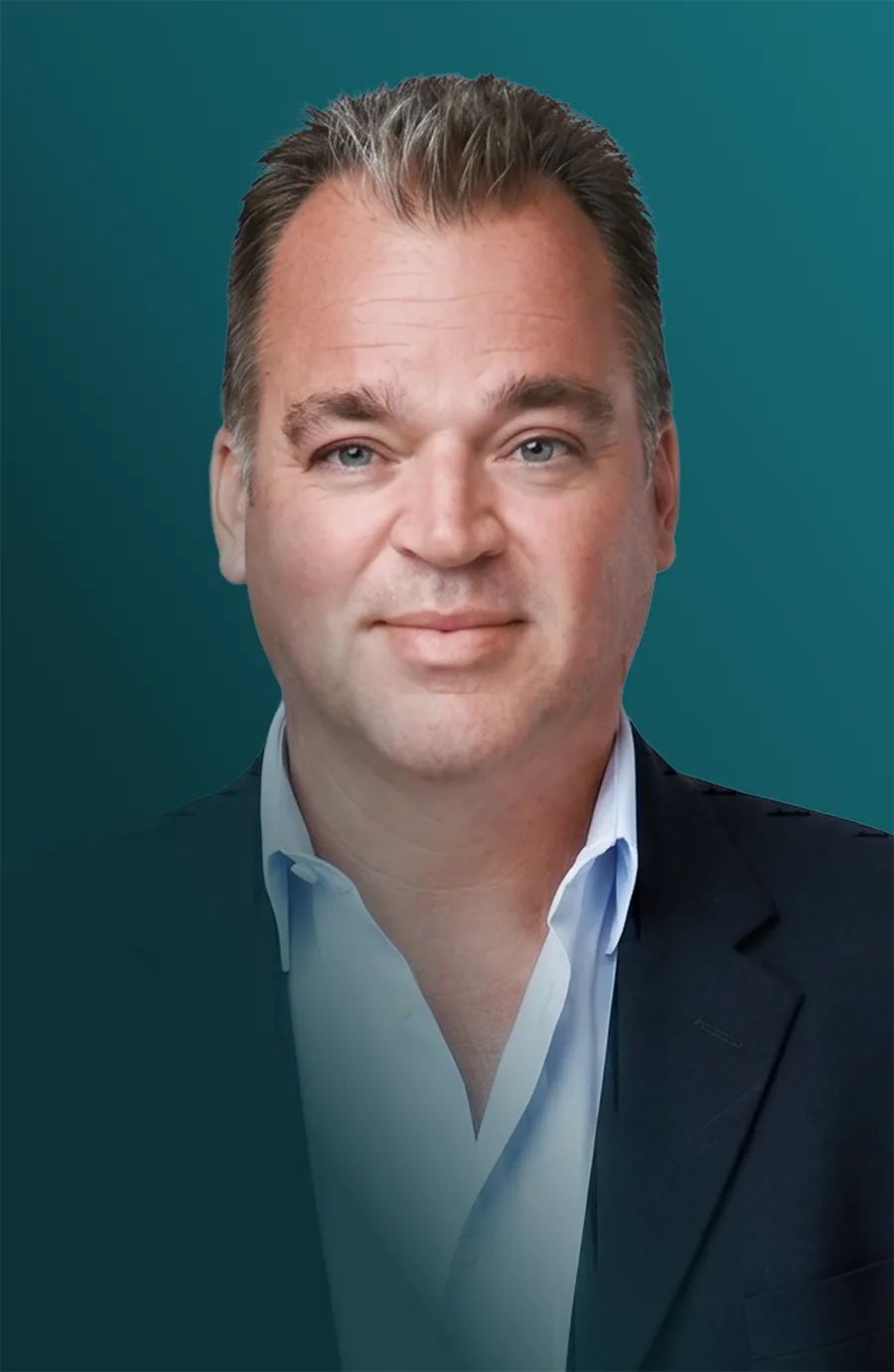 Portrait of a man with short gray hair smiling, wearing a dark blazer over a light blue button-down shirt, against a teal background.