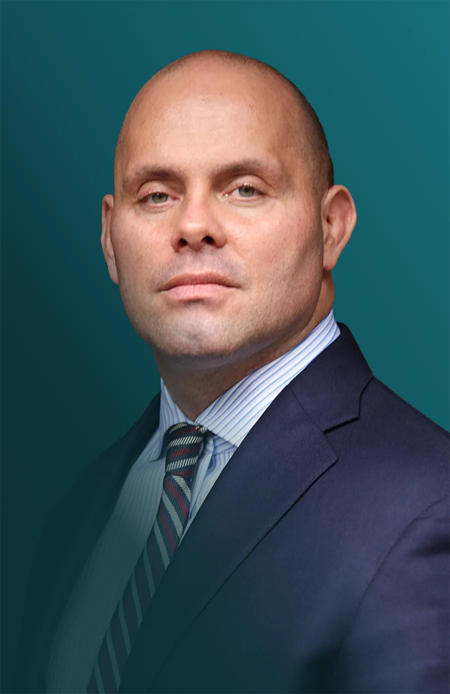 Portrait of a bald man wearing a dark suit jacket, a blue and white striped shirt, and a patterned tie against a teal background.