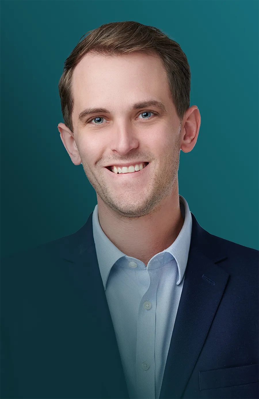 Portrait of a young man with light brown hair and blue eyes smiling, wearing a light blue shirt and dark blue blazer, with a teal background.