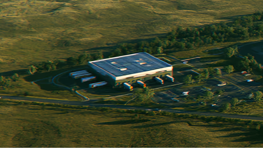 Aerial view of a warehouse with delivery trucks parked outdoors in a rural area.