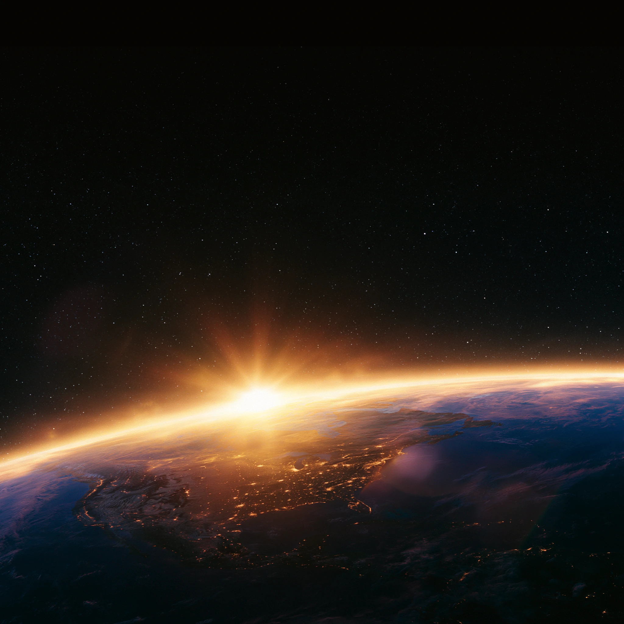 Sunrise over Earth from space showing the planet's illuminated horizon and starry background.