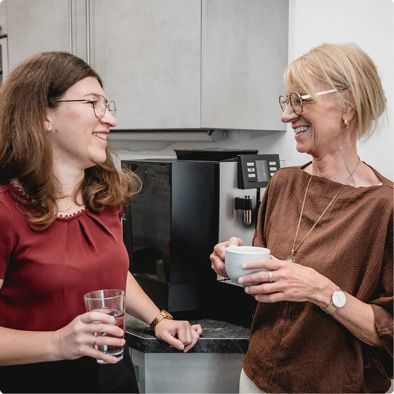 Zwei Kolleginnen im Gespräch an der Kaffeemaschine