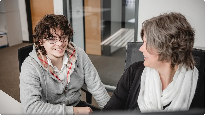 Zwei Kolleginnen lachen im Gespräch