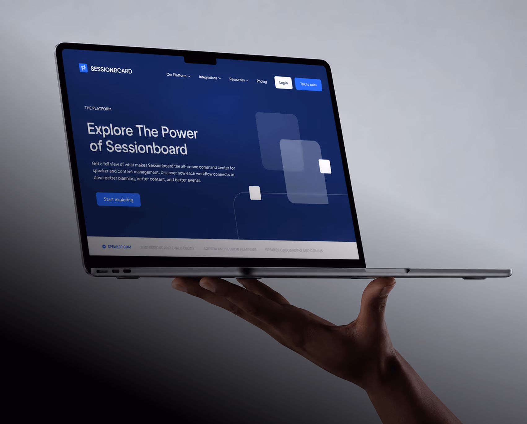 Hand balancing a MacBook showing the Sessionboard website hero "Explore The Power of Sessionboard" on a dark blue layout