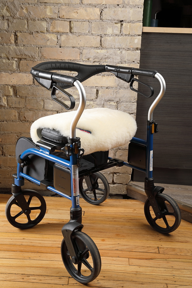 A sheepskin Bumwarmer cushioning the seat of a blue rollator walker