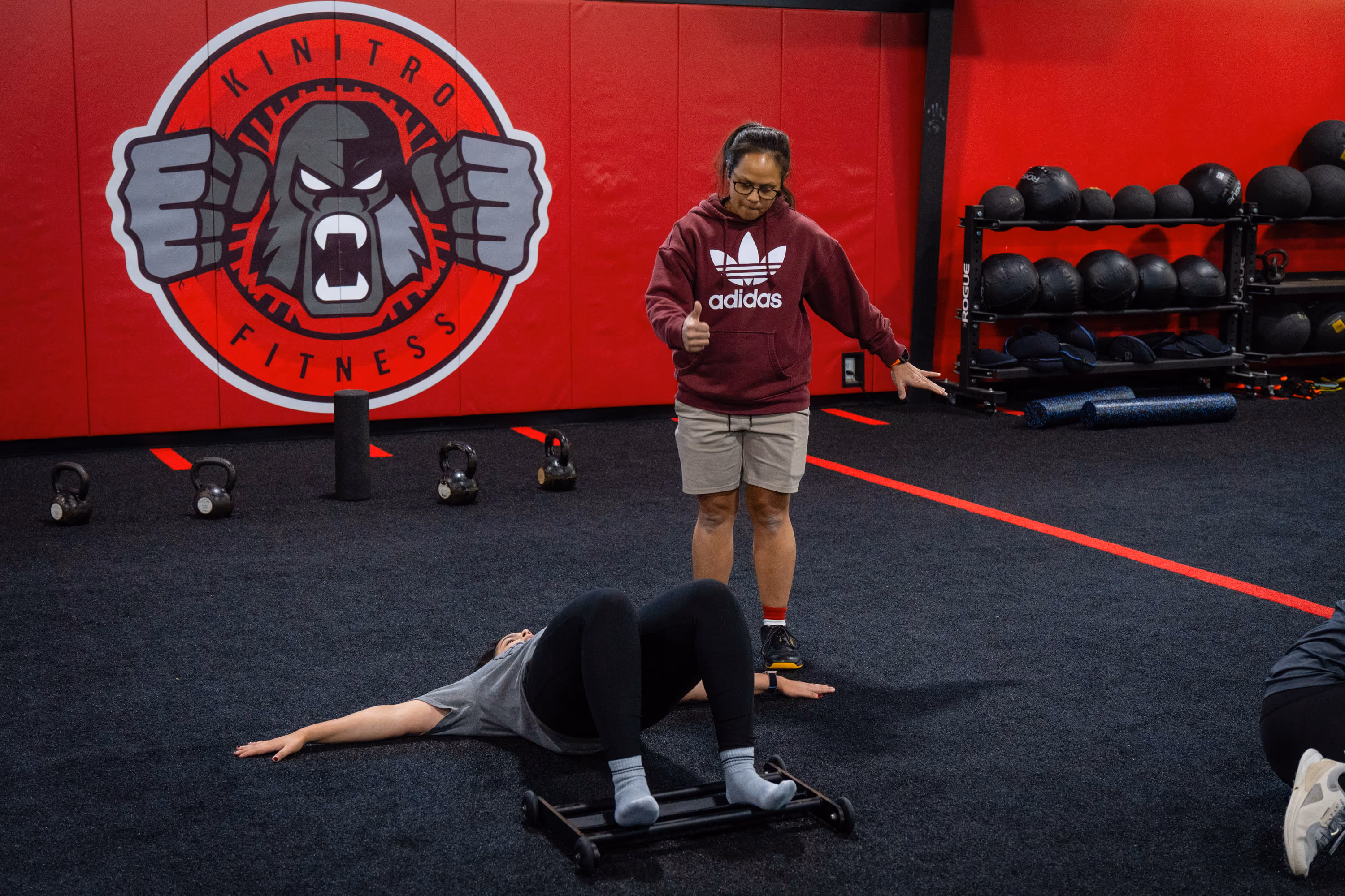 Coach guiding a member through a floor exercise at Kinitro Fitness