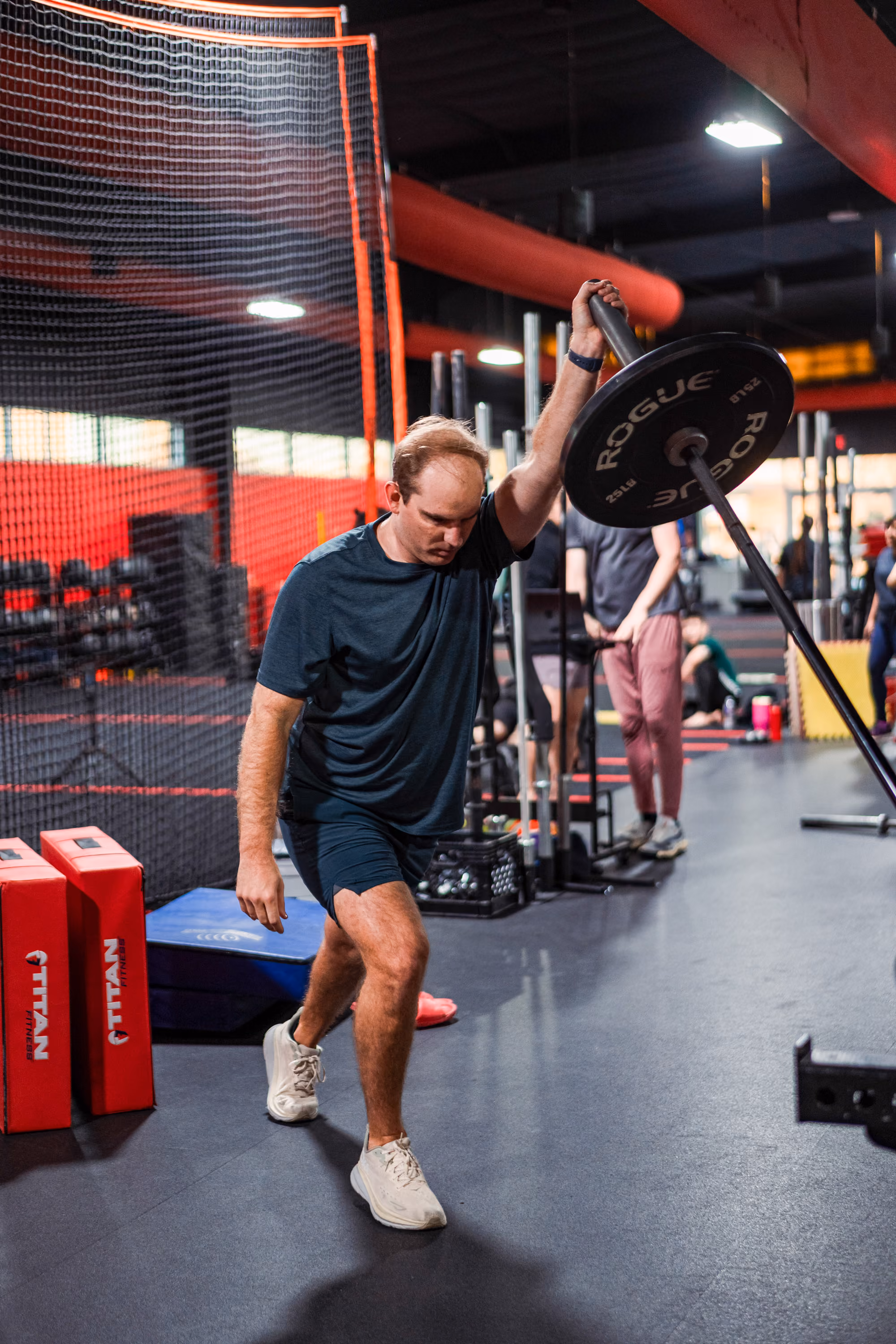 Man performing overhead barbell lockout at Kinitro Fitness.